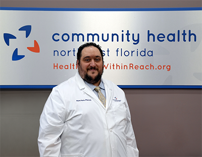 Anthony Pinto standing in front of a sign saying "Community Health Northwest Florida"