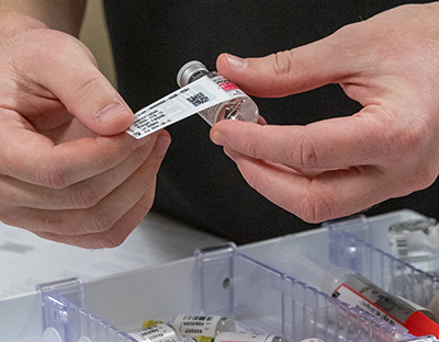 Hands tagging a vial of medication with a bar code