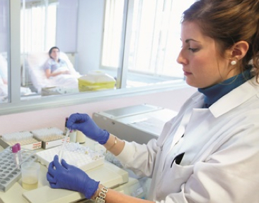Pharmacist prepares medication while a patient looks on