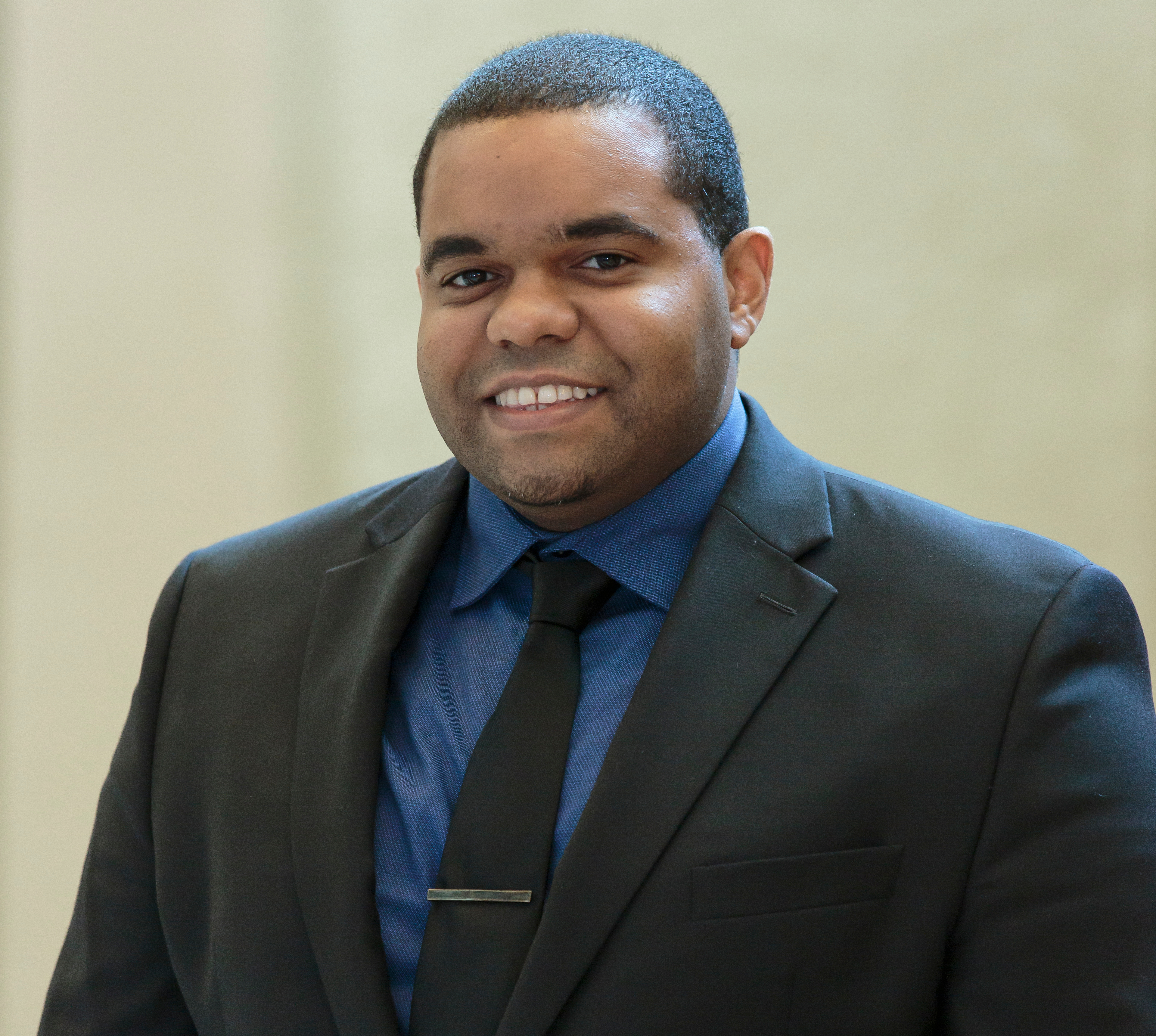 Male pharmacy student in a suit smiling at the camera